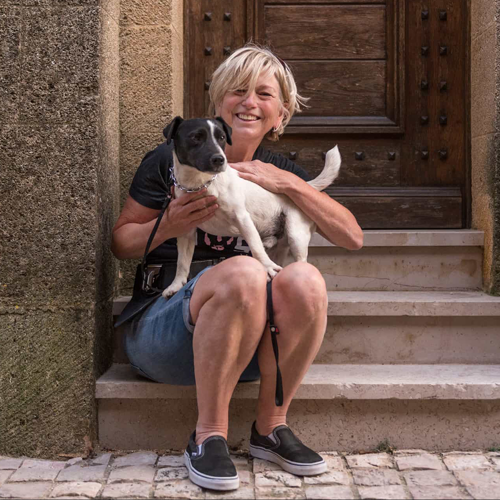 Photo of Karen Black sitting on stone doorstep with dog on her lap
