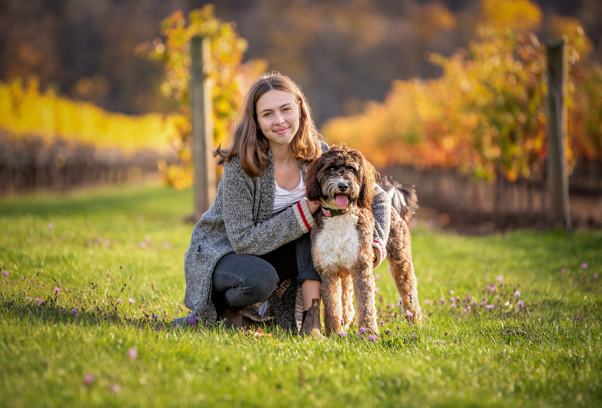 Young woman and her dog in niagara vineyard wearing fall sweater and boots